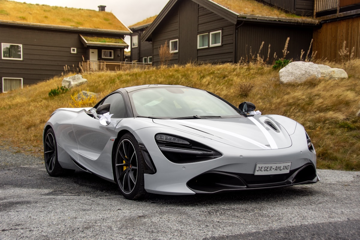 Grey sports coupe parked outdoors with trees in the background